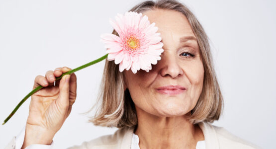 Women smiling holding flower up to her face