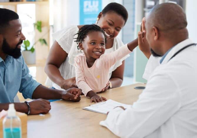 Girl with her parents high fives family medicine doctor